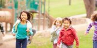 Group Of Young Children Running In Park