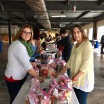 20180101 FP 2 women volunteers at packing table with plastic bags of food