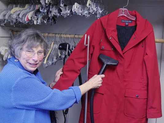 Assistance League volunteer, Roz Worchester, prepares a coat for sale by steaming away any wrinkles that it might have gotten when folded. (Photo: Special to the Statesman Journal)